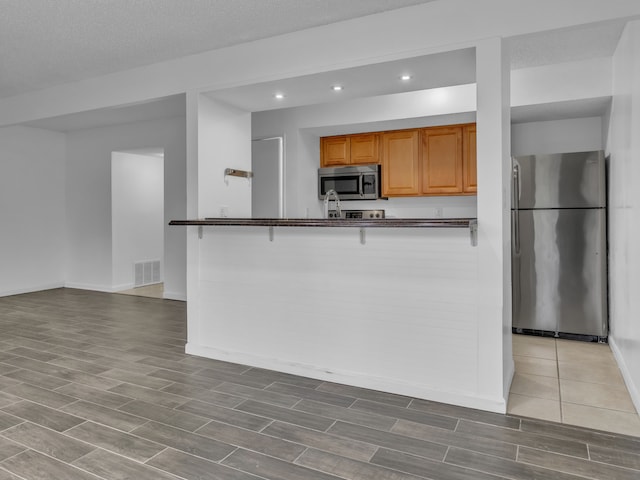 2401 Packard St Unit 31D, Ann Arbor, MI 48104 - kitchen featuring wood tiled floor, recessed lighting, visible vents, dark countertops, and stainless steel appliances