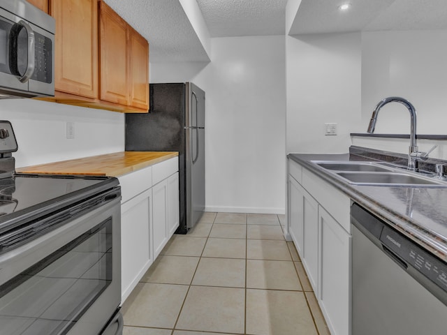 2401 Packard St Unit 31D, Ann Arbor, MI 48104 - kitchen featuring recessed lighting, light tile patterned floors, a sink, stainless steel appliances, and white cabinets