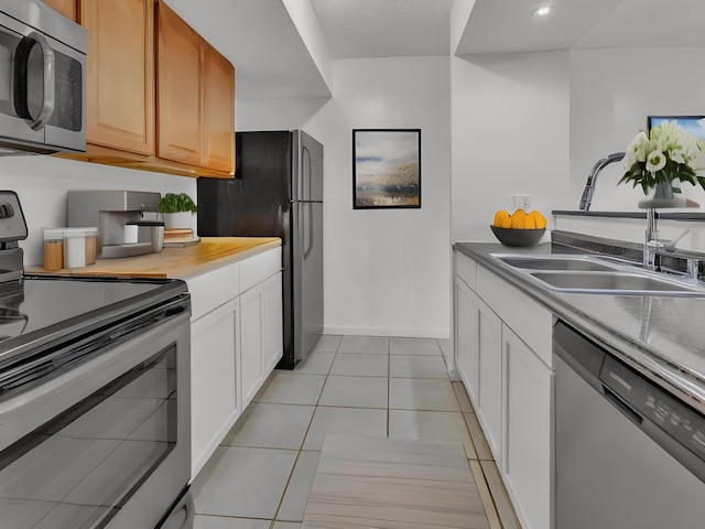 2401 Packard St Unit 31D, Ann Arbor, MI 48104 - kitchen with recessed lighting, light tile patterned floors, baseboards, a sink, and stainless steel appliances