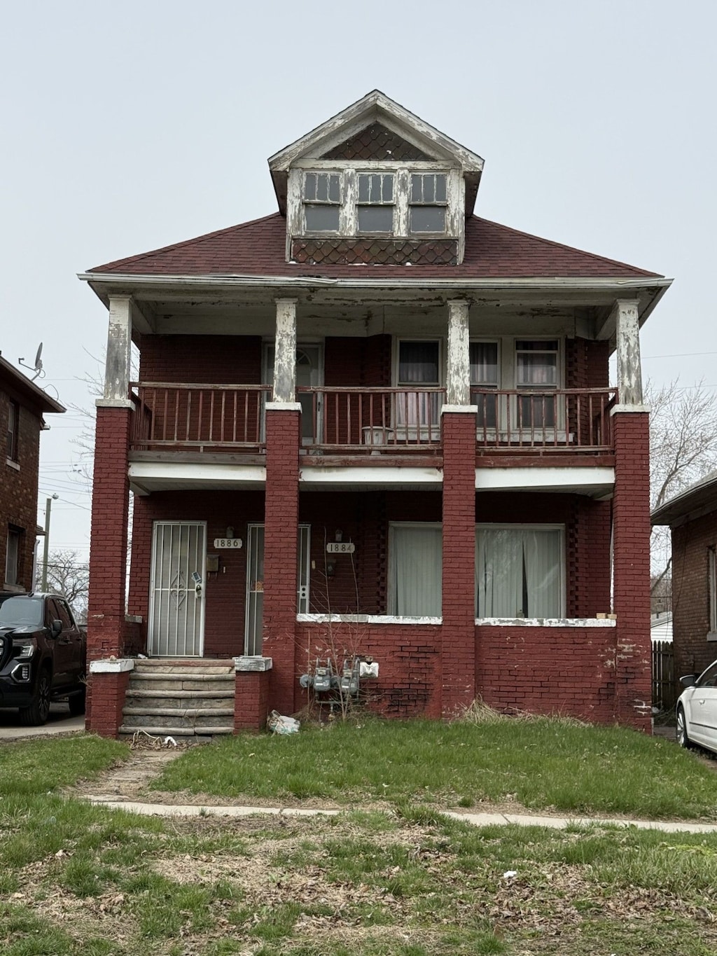 1884 S Liddesdale St, Detroit, MI 48217 - view of front of house featuring roof with shingles, brick siding, a balcony, and a front lawn