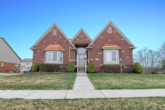 view of front of house with brick siding, a front lawn, and a standing seam roof