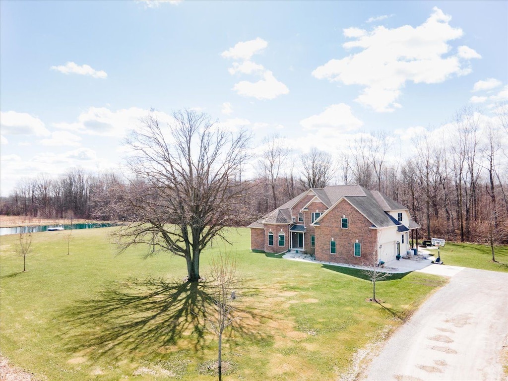 view of front facade featuring a front yard, brick siding, a garage, and driveway