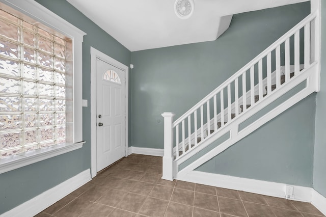 tiled entryway featuring baseboards and stairway