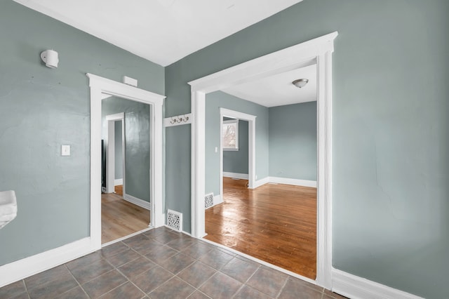 spare room featuring dark wood-style flooring, baseboards, and visible vents