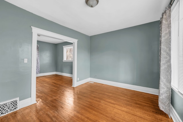 empty room with visible vents, baseboards, and wood finished floors