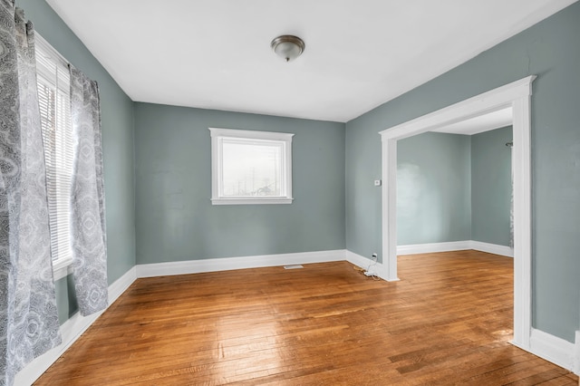 empty room with hardwood / wood-style flooring and baseboards