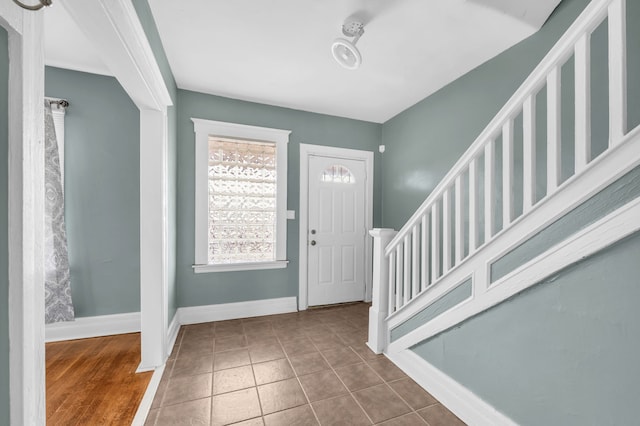 tiled entrance foyer featuring baseboards and stairway