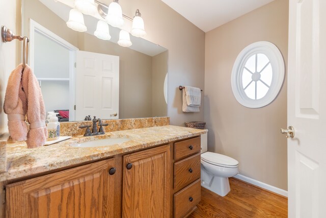7837 Oak River Dr, Grosse Ile, MI 48138 - bathroom featuring toilet, vanity, wood finished floors, and baseboards