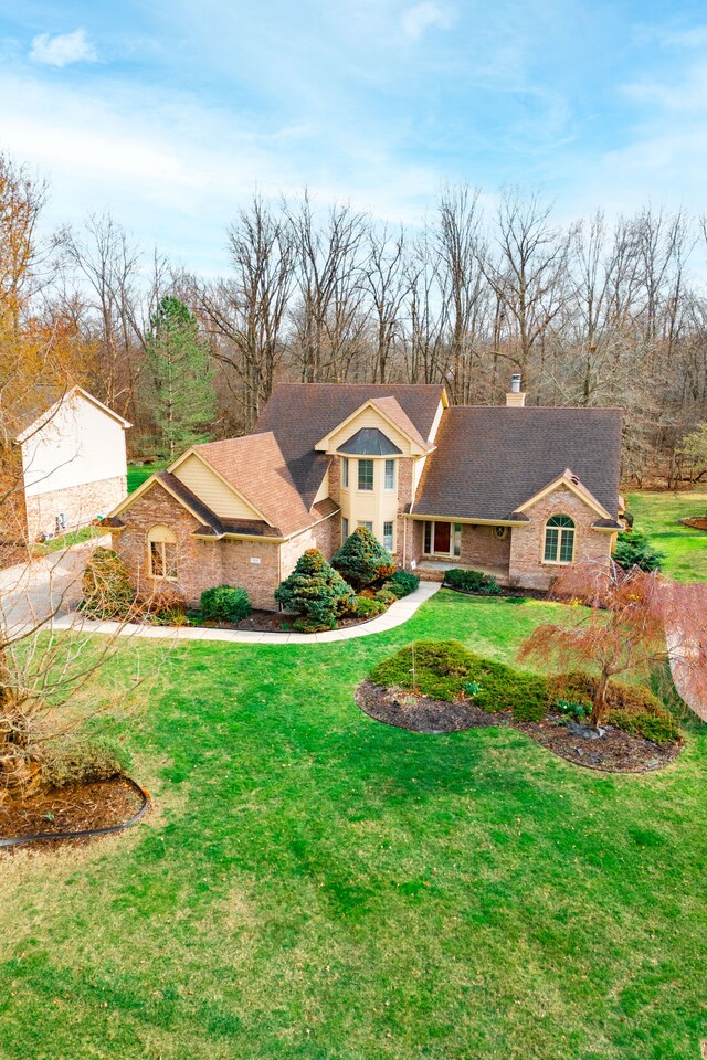 7837 Oak River Dr, Grosse Ile, MI 48138 - view of front facade with a front yard, a chimney, brick siding, and roof with shingles