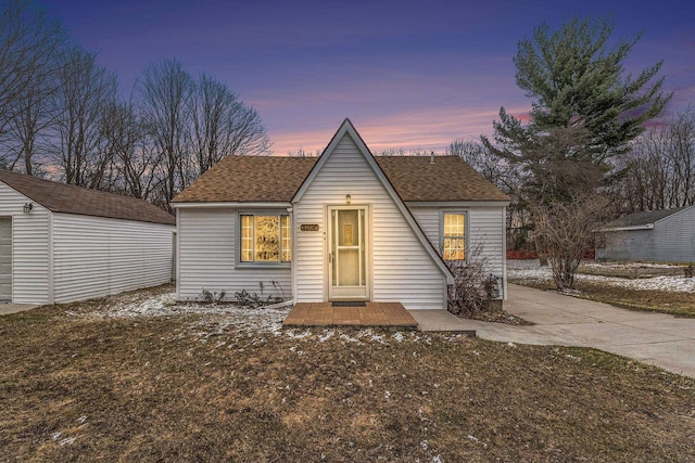 view of front of home with a shingled roof and an outbuilding