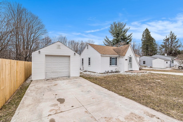 view of front of house featuring concrete driveway, an outbuilding, a garage, and fence