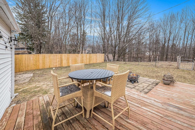 wooden deck featuring outdoor dining area, fence, and an outdoor fire pit