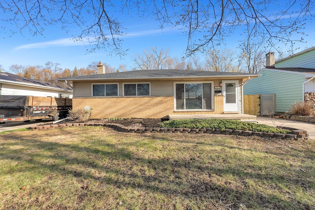 rear view of house with a lawn, fence, and brick siding