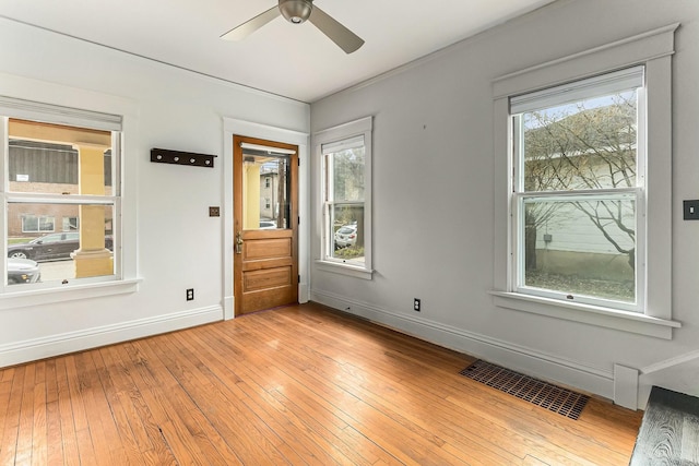 empty room with visible vents, ceiling fan, light wood-style floors, and baseboards