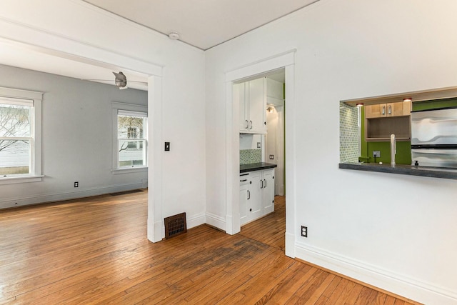 empty room with hardwood / wood-style floors, baseboards, and visible vents