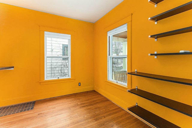 spare room featuring visible vents, baseboards, and wood finished floors