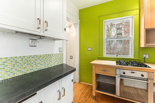 kitchen with white cabinets, oven, black gas cooktop, light wood finished floors, and decorative backsplash