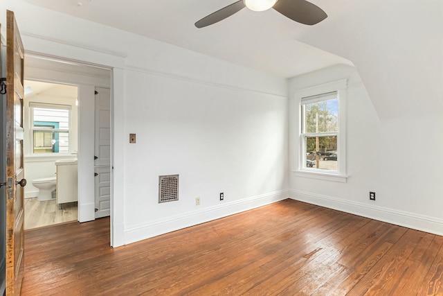 spare room featuring baseboards, vaulted ceiling, a ceiling fan, visible vents, and hardwood / wood-style floors