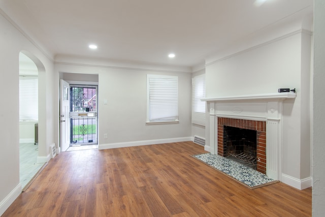 9661 Asbury Park, Detroit, MI 48227 - unfurnished living room featuring arched walkways, wood finished floors, visible vents, and a brick fireplace