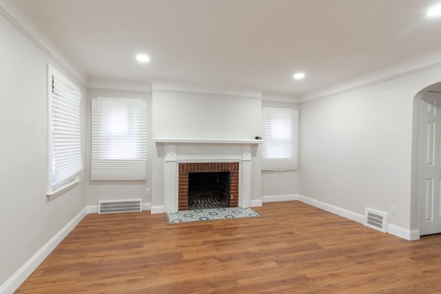 9661 Asbury Park, Detroit, MI 48227 - unfurnished living room featuring arched walkways, a brick fireplace, visible vents, and light wood-style floors