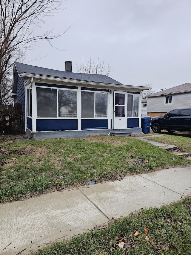 494 Polk Ave, River Rouge, MI 48218 - view of front of house featuring a chimney, a sunroom, and a front yard