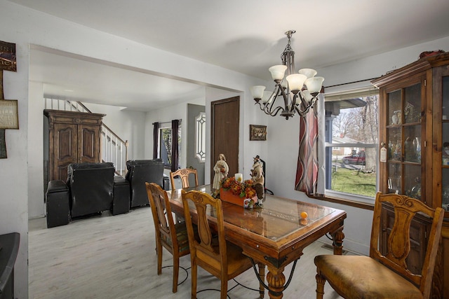 dining space featuring light wood-style flooring, an inviting chandelier, plenty of natural light, and stairs