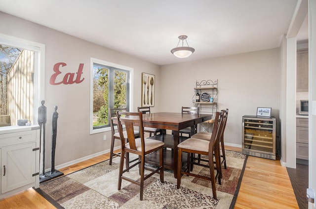 dining room featuring light wood-type flooring, beverage cooler, and baseboards