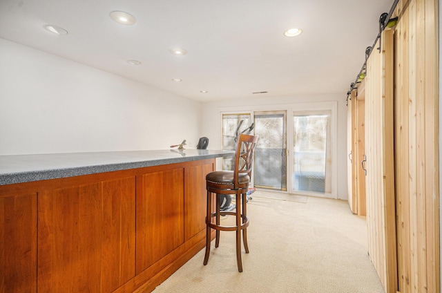 bar with a bar, light colored carpet, recessed lighting, and a barn door