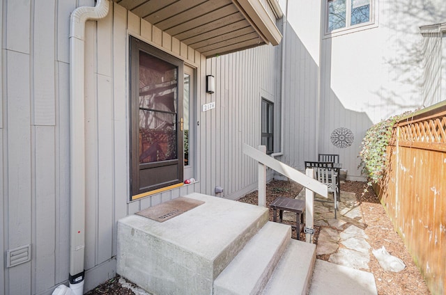 property entrance with board and batten siding and fence