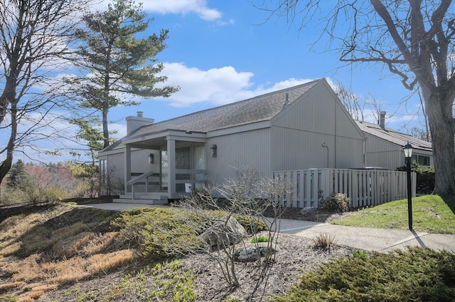 back of house with roof with shingles, fence, and a chimney