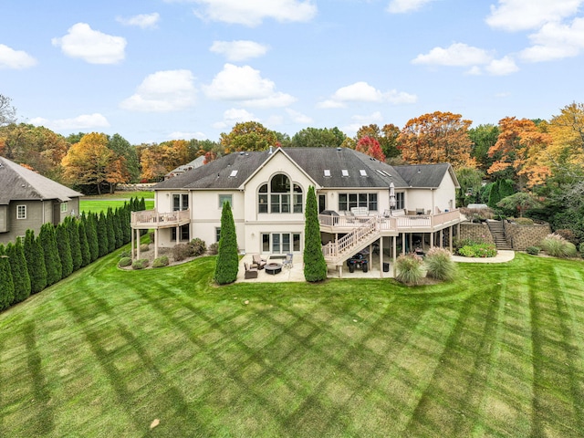 rear view of property featuring a patio, stucco siding, stairway, a yard, and a deck