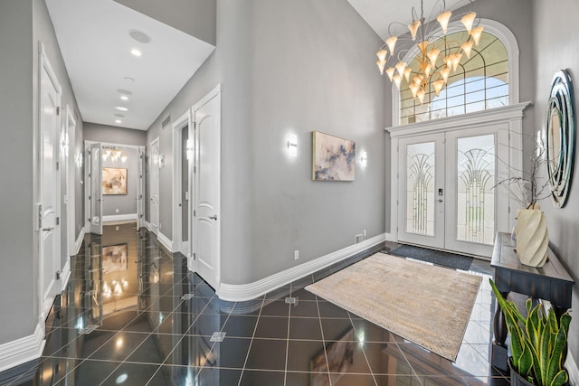 entryway featuring an inviting chandelier, a high ceiling, granite finish floor, french doors, and baseboards
