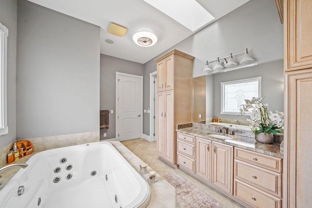 full bathroom featuring tile patterned floors, vanity, a tub with jets, and a skylight