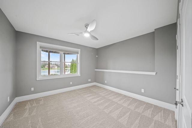 carpeted empty room featuring baseboards and a ceiling fan