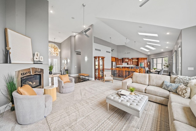 carpeted living room with high vaulted ceiling, recessed lighting, a tile fireplace, and a skylight