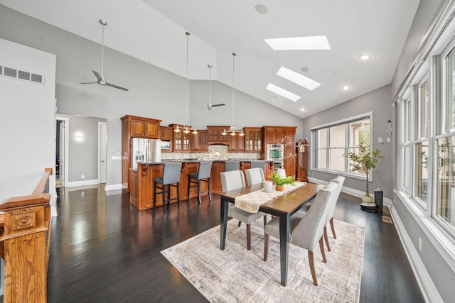 dining space featuring visible vents, baseboards, dark wood-style flooring, ceiling fan, and a skylight