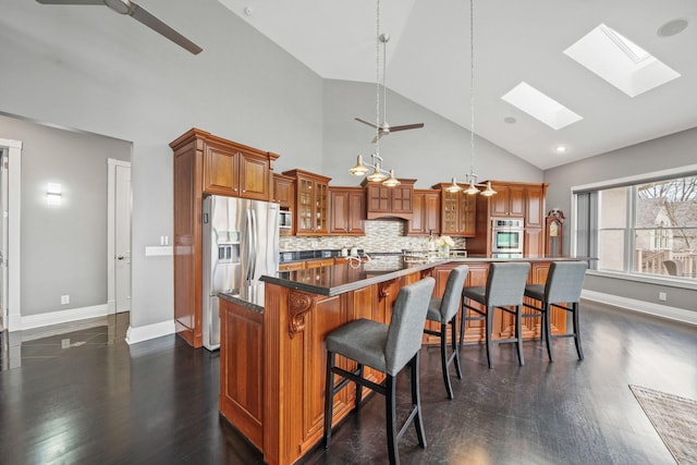 kitchen featuring a large island, a ceiling fan, brown cabinetry, a skylight, and stainless steel appliances
