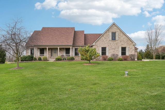 view of front facade featuring a front yard, brick siding, and covered porch