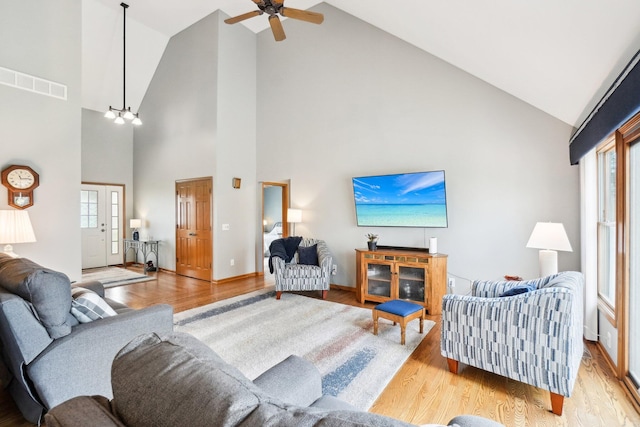 living area featuring visible vents, light wood-style flooring, a ceiling fan, and vaulted ceiling