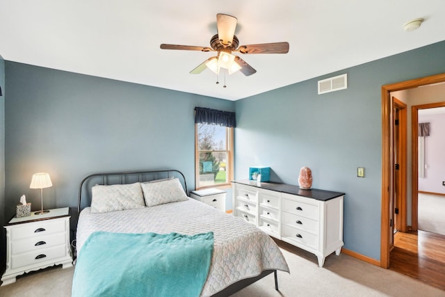 bedroom with visible vents, baseboards, a ceiling fan, and light carpet