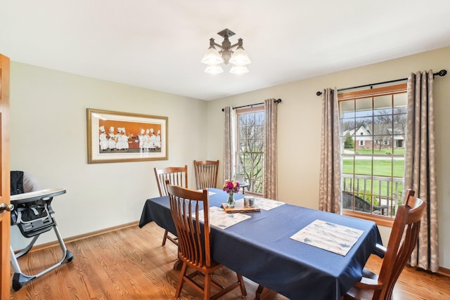 dining space featuring baseboards, an inviting chandelier, and wood finished floors