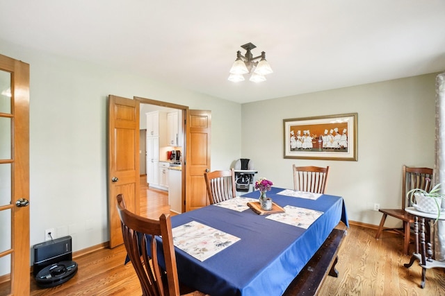 dining room with baseboards, a chandelier, and light wood-style floors