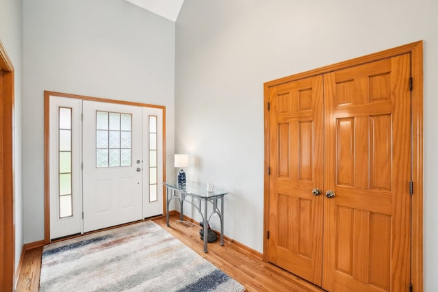 foyer with a high ceiling, light wood-type flooring, and baseboards