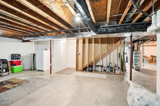 unfinished basement with water heater and freestanding refrigerator