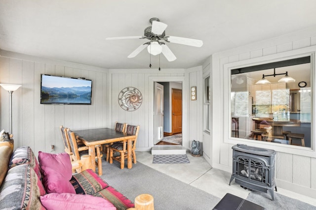 living area featuring a wood stove and ceiling fan