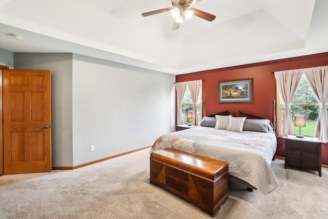 bedroom with a tray ceiling, carpet flooring, baseboards, and a ceiling fan