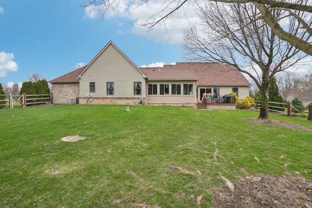 back of property featuring a wooden deck, central air condition unit, a lawn, fence, and brick siding