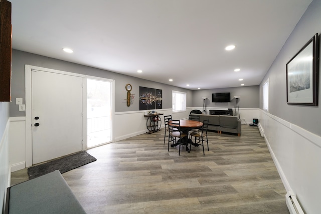 dining space featuring a baseboard radiator, wood finished floors, wainscoting, and recessed lighting