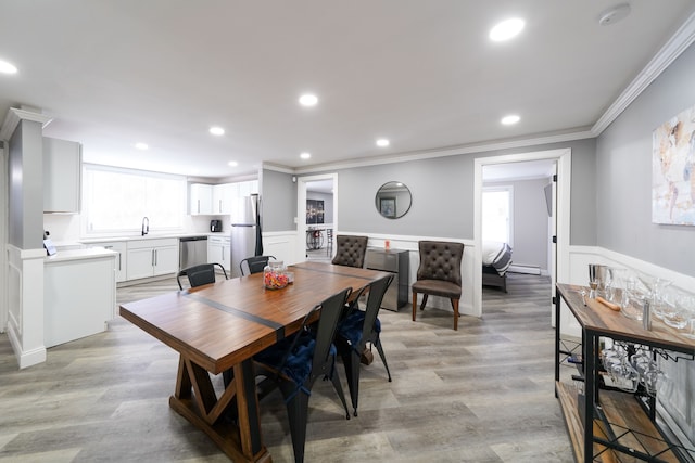 dining room with ornamental molding, a wainscoted wall, recessed lighting, and light wood-style floors