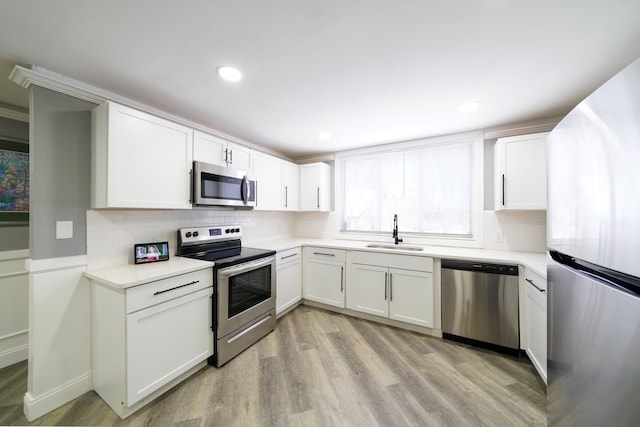kitchen with stainless steel appliances, tasteful backsplash, light wood-type flooring, and a sink